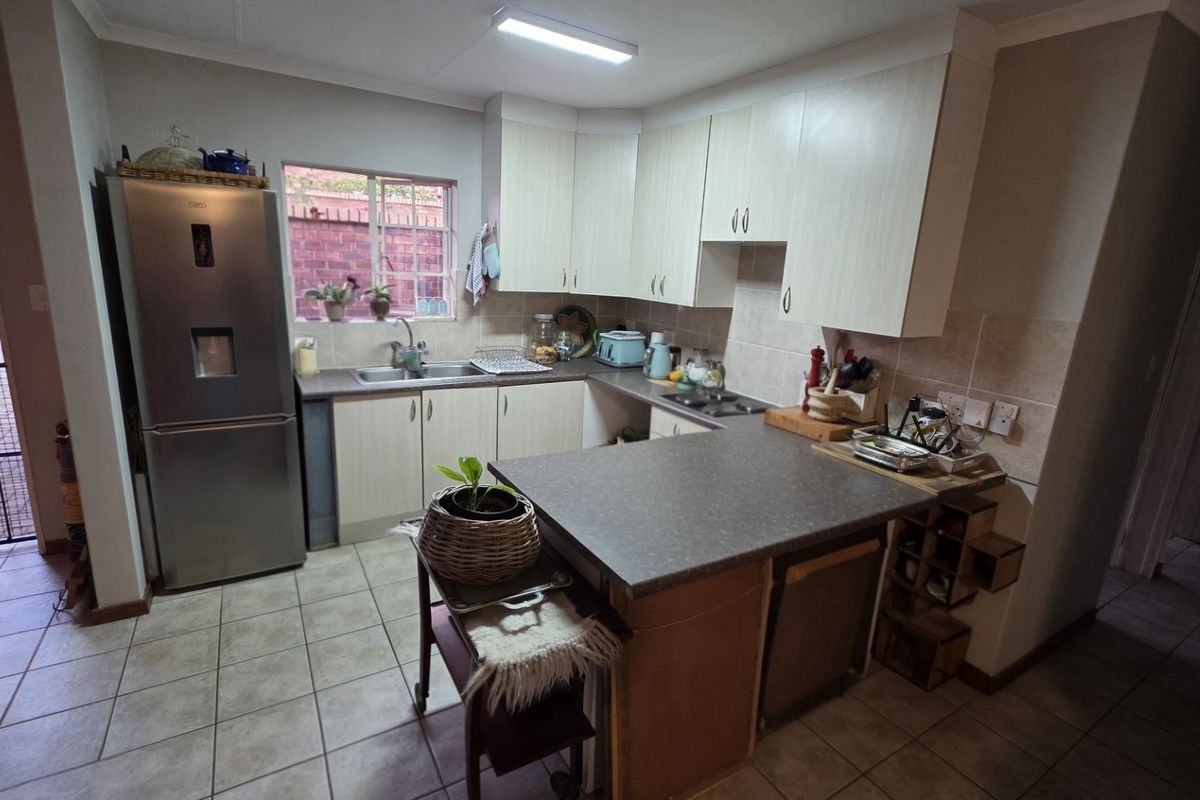 Functional kitchen featuring light-toned cabinetry, laminate countertops, a stainless steel sink, and tiled flooring, with direct access to the exterior.