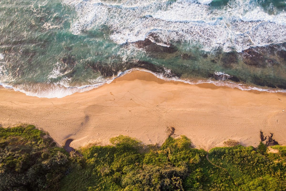 An aerial view of the coastal property, showcasing direct beach access and natural landscape.