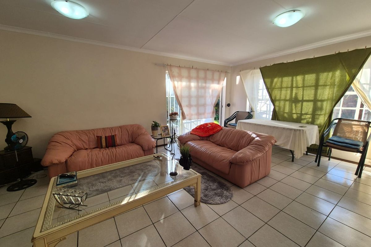 Spacious living area featuring neutral tiled flooring, large windows allowing natural light, and direct access to the outdoor patio area.