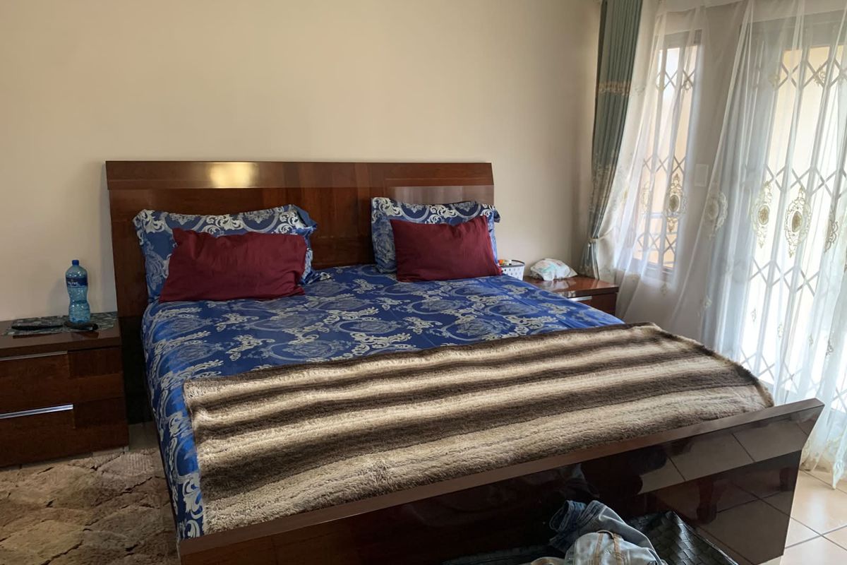 A bedroom featuring tiled flooring and a sliding glass door with security gate, providing access to the exterior.