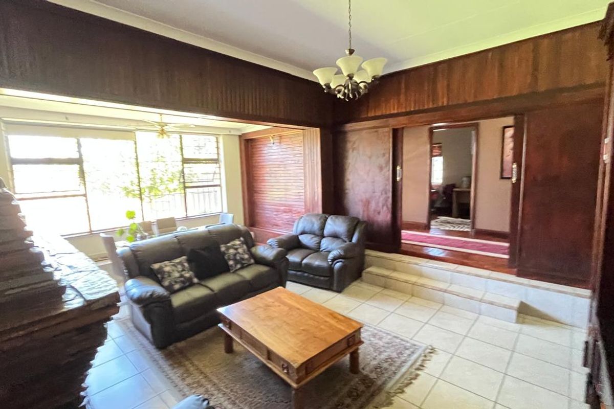 Spacious living area featuring a raised floor section, traditional wood wall paneling, and large windows allowing for natural light.