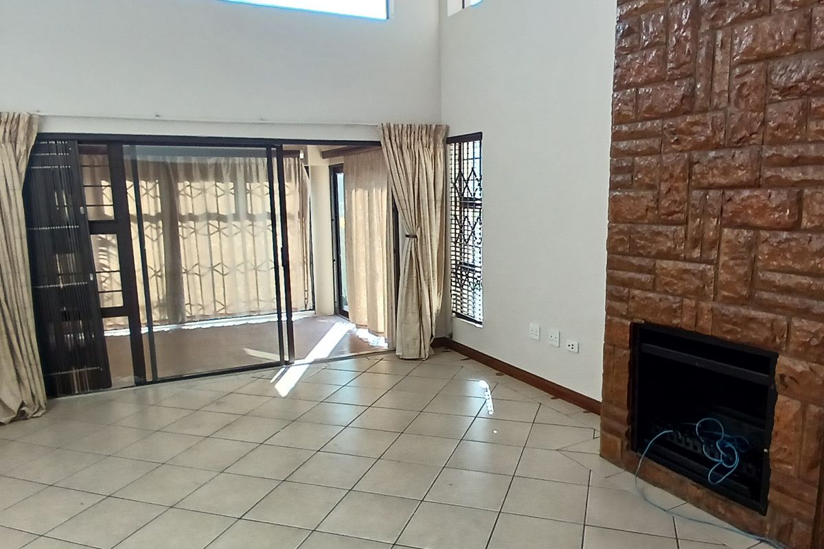Spacious living room featuring a prominent stone-clad fireplace, tiled flooring, and large sliding glass doors providing access to the patio area.