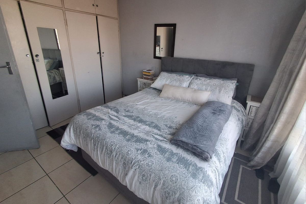 A bedroom featuring built-in cupboards with integrated mirror and tiled flooring.