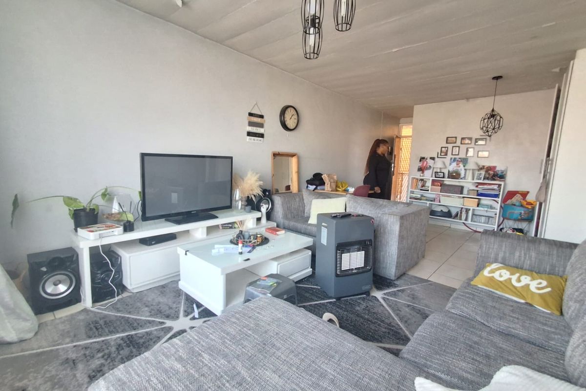 A living room area featuring tiled flooring and pendant lighting, with visible wear to the ceiling finish.