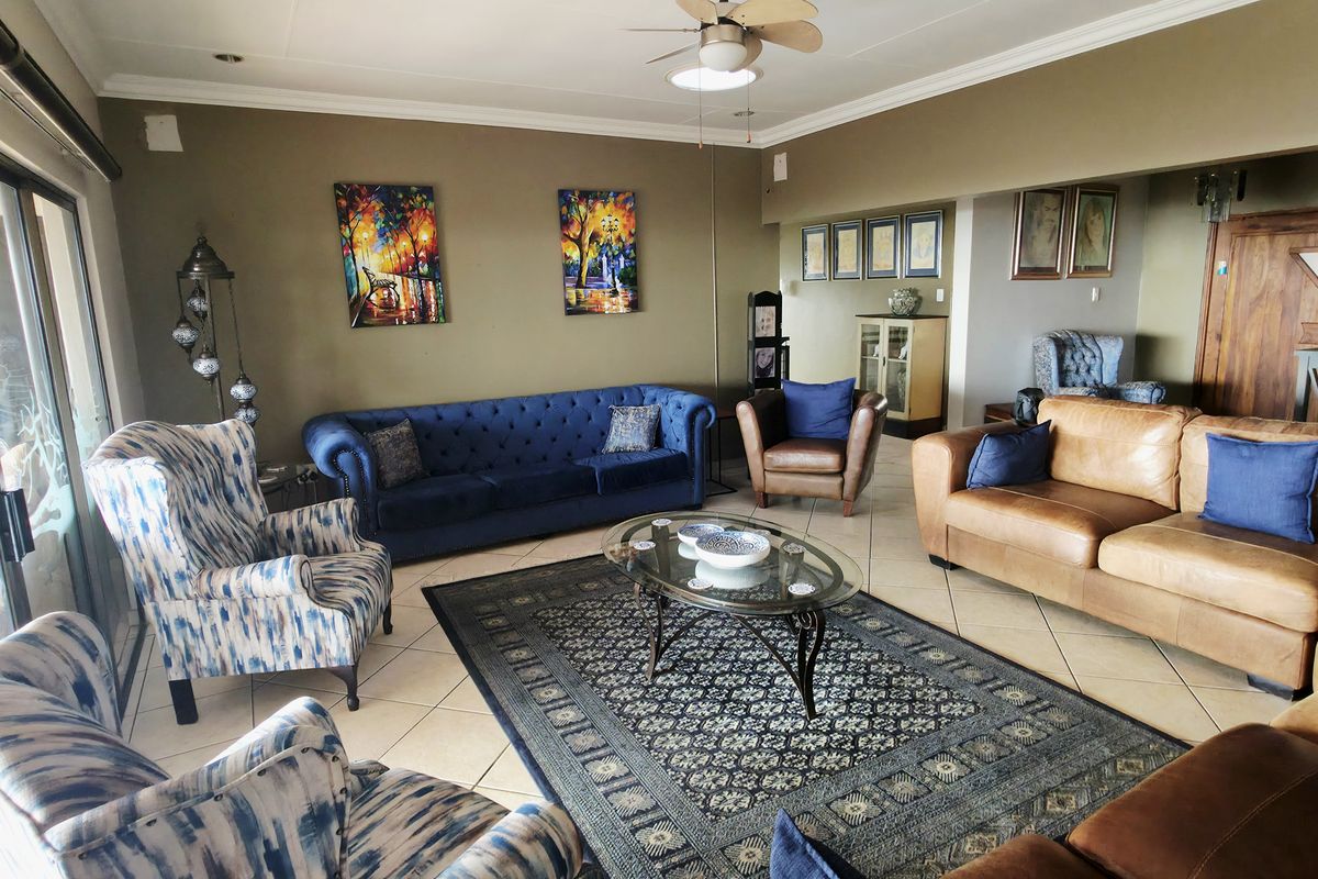 Spacious living room featuring tiled flooring, a ceiling fan, and large sliding glass doors providing natural light and access to the exterior.