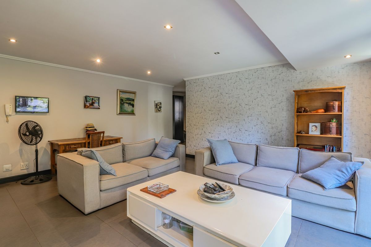 A spacious living room featuring tiled flooring, recessed ceiling lighting, and a decorative feature wall.