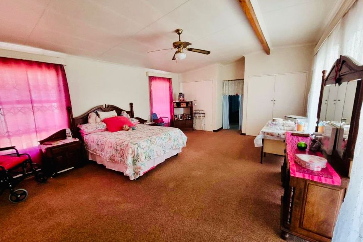 Spacious bedroom featuring built-in cupboards, a ceiling fan, and large windows allowing for natural light.