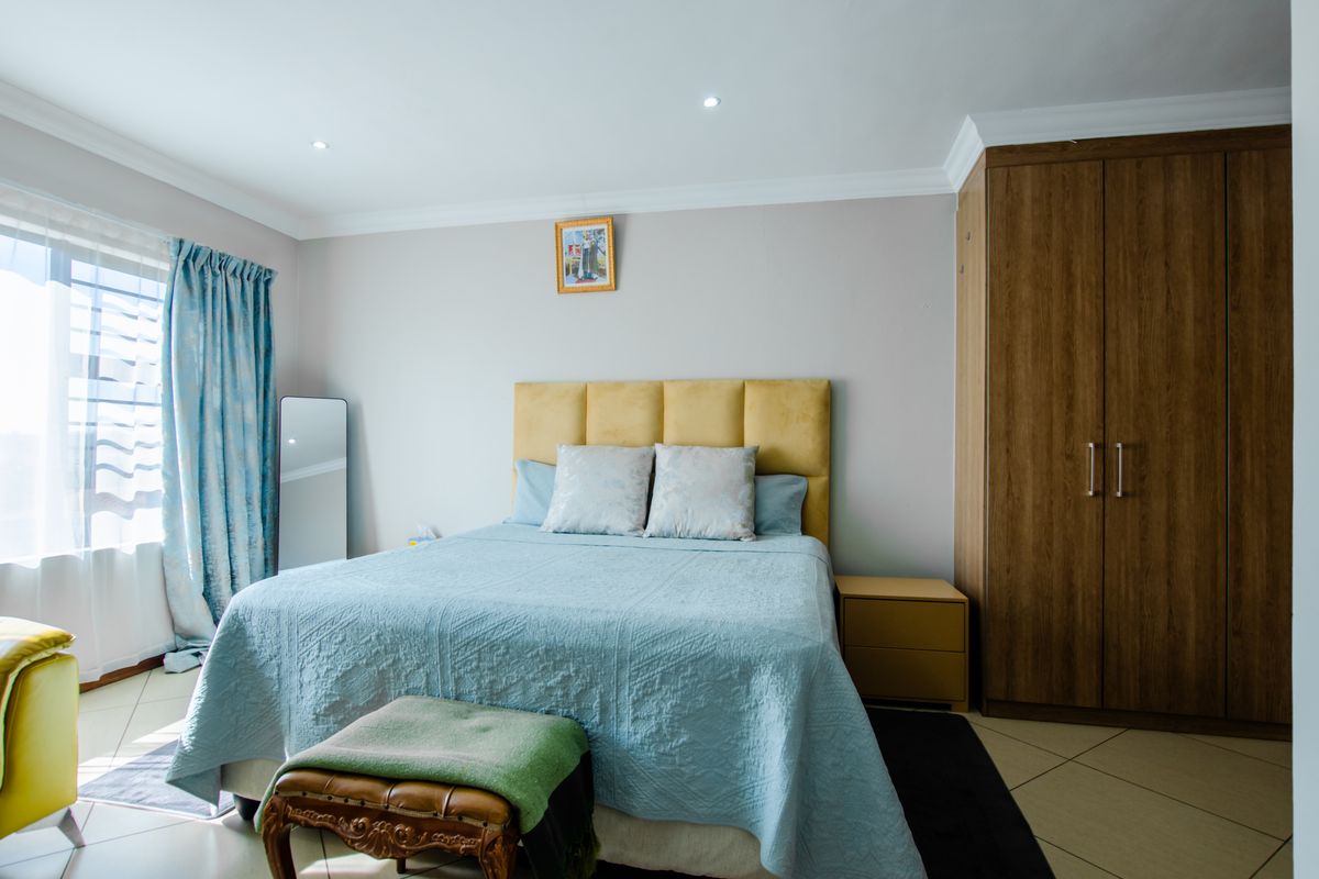 A well-maintained bedroom featuring tiled flooring, recessed downlighting, decorative cornicing, and a large built-in wardrobe.