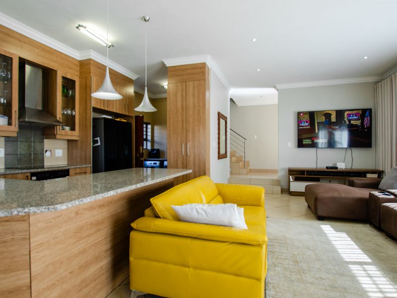 Spacious open-plan living area featuring a modern kitchen with granite countertops, wooden cabinetry, and a seamless flow to the lounge and staircase.