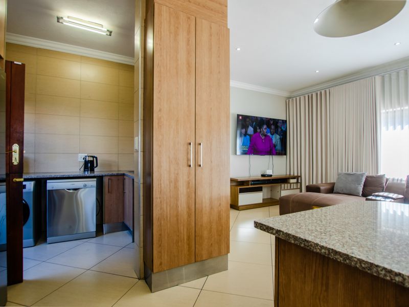 An open-plan living area featuring a kitchen with granite countertops and built-in cabinetry, seamlessly flowing into a comfortable lounge space.