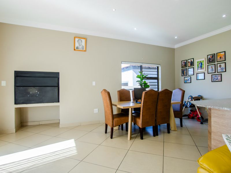 Open-plan living and dining area featuring tiled floors, recessed lighting, and a built-in fireplace, seamlessly connecting to the kitchen space.
