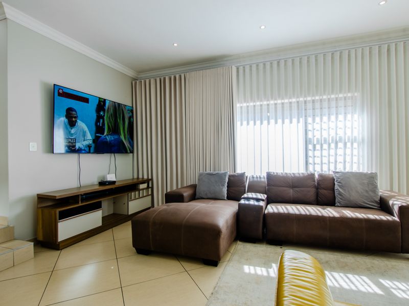 A well-maintained living room featuring tiled flooring, recessed downlighting, and floor-to-ceiling curtain tracks, creating a bright and functional living space.