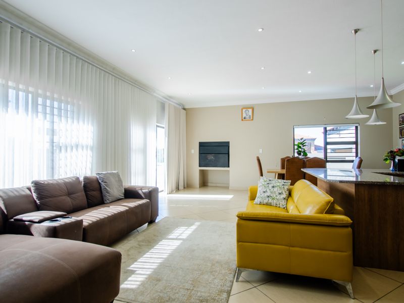 Spacious open-plan living and dining area featuring tiled floors, recessed lighting, a built-in fireplace, and a modern kitchen island with pendant lights.