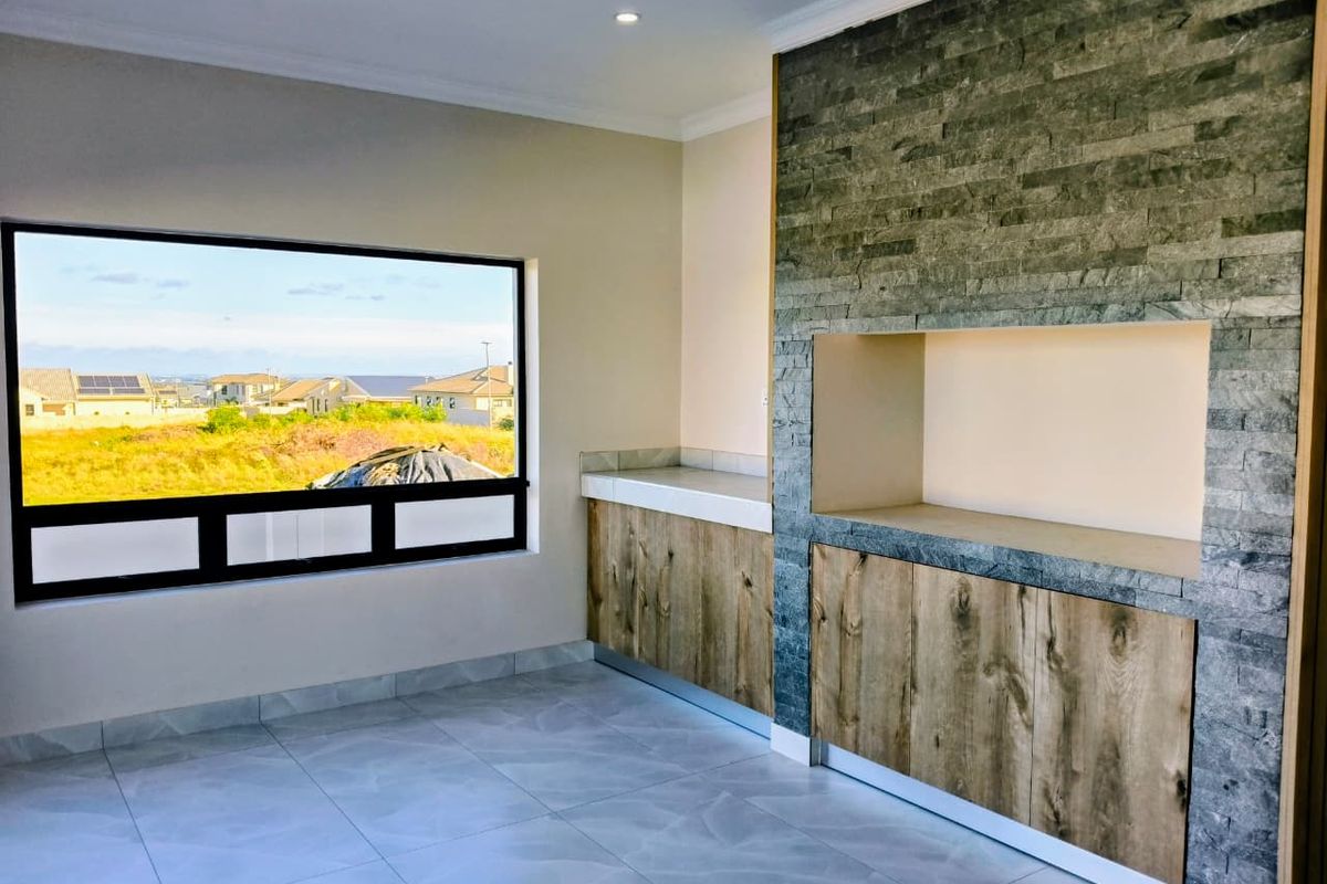 A modern living area featuring a stone-clad built-in feature wall with cabinetry and large windows offering neighborhood views.