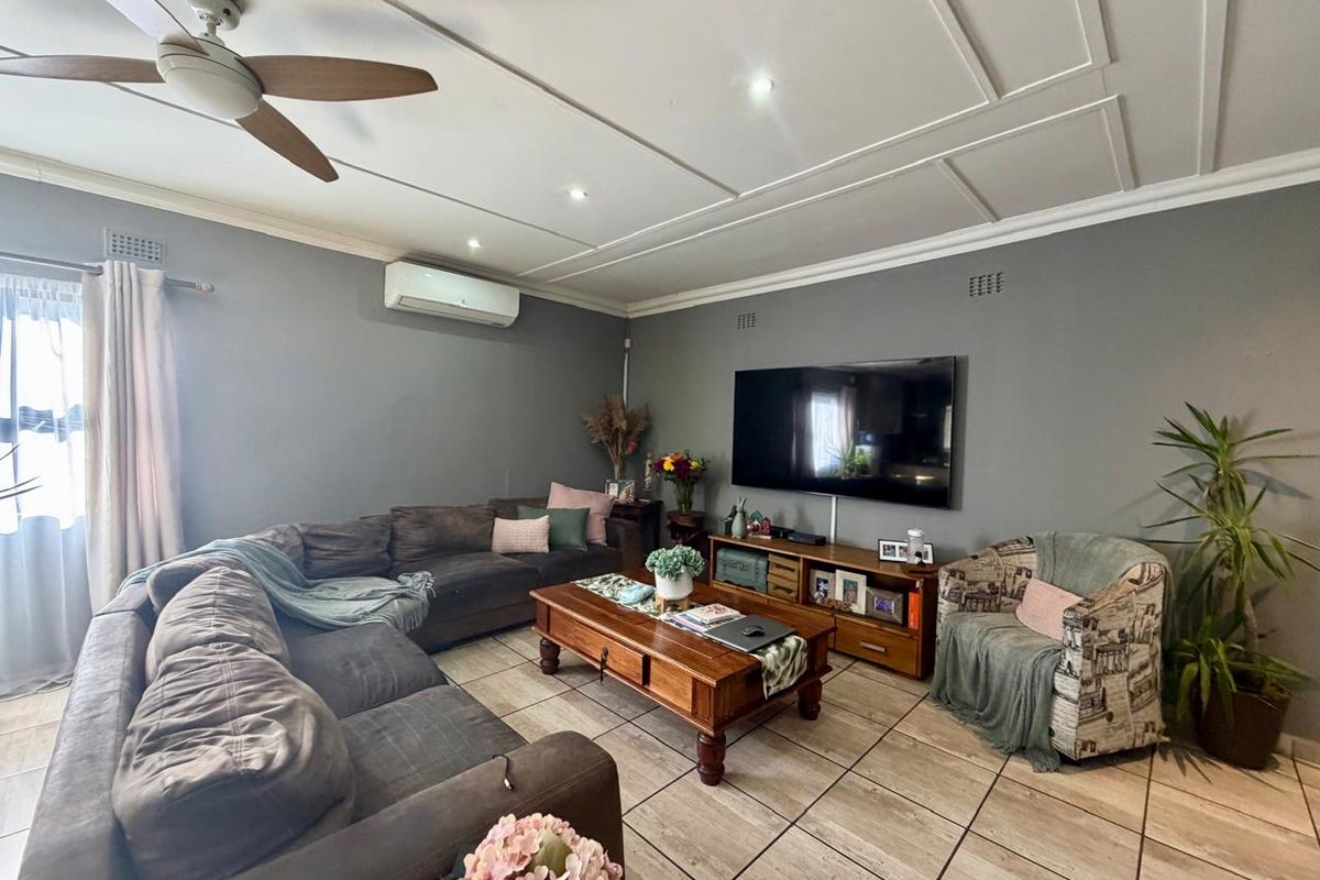 A comfortable living room featuring tiled flooring, a ceiling fan, and a wall-mounted air conditioning unit.