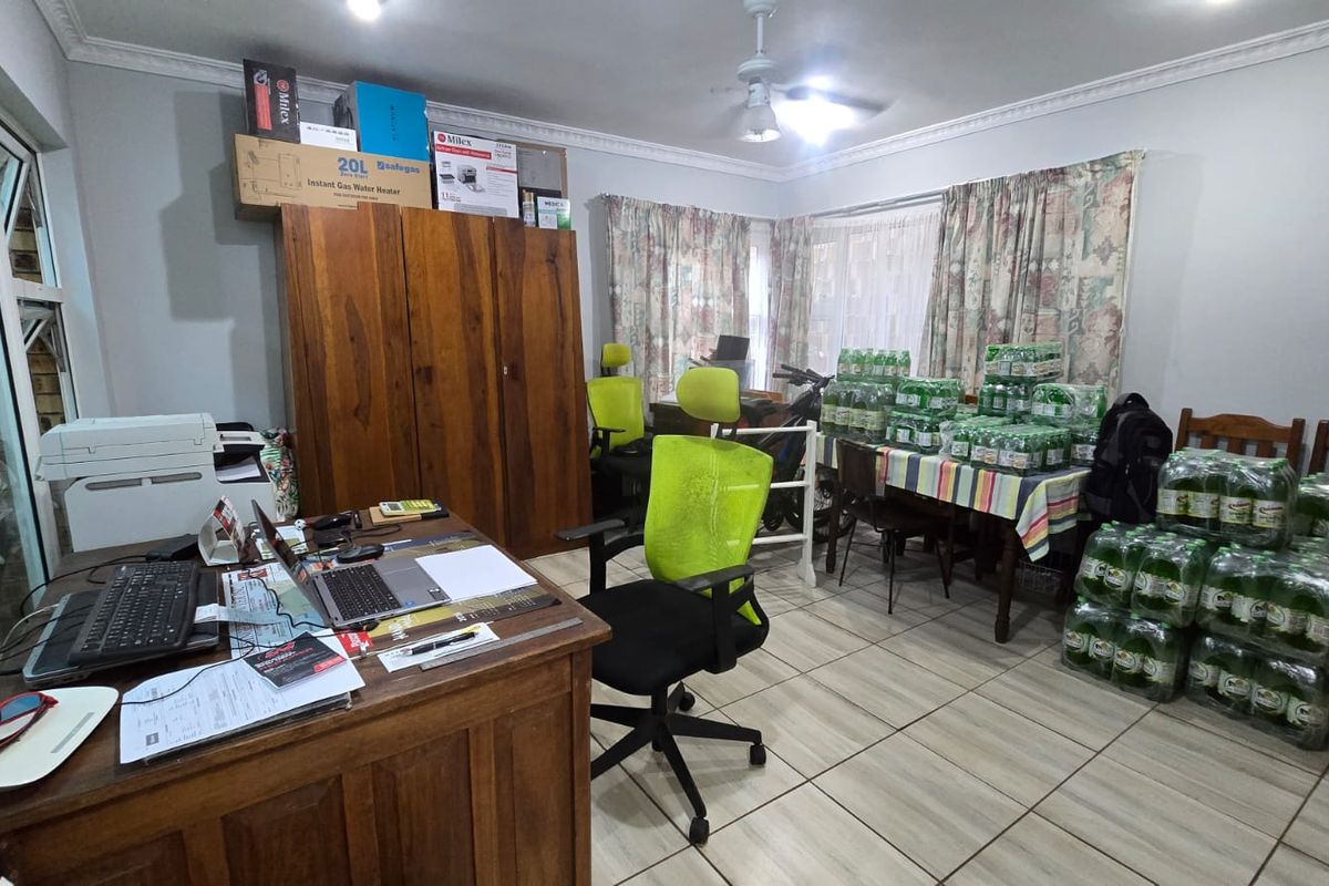 A multi-purpose room featuring tiled flooring and crown molding, currently utilized as a home office and storage area.