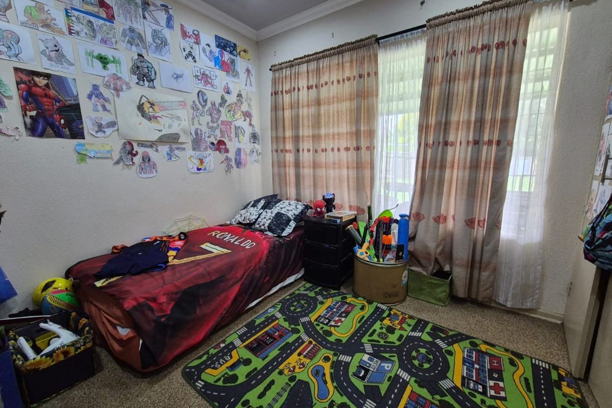 A functional bedroom featuring carpeted flooring, large windows with fitted curtain tracks, and recessed ceiling lighting.