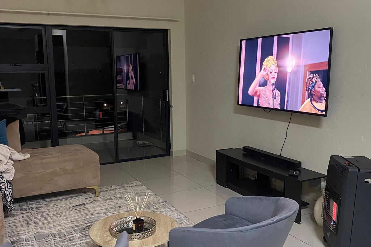 Spacious living area featuring high ceilings, large sliding glass doors leading to a balcony, and tiled flooring throughout.