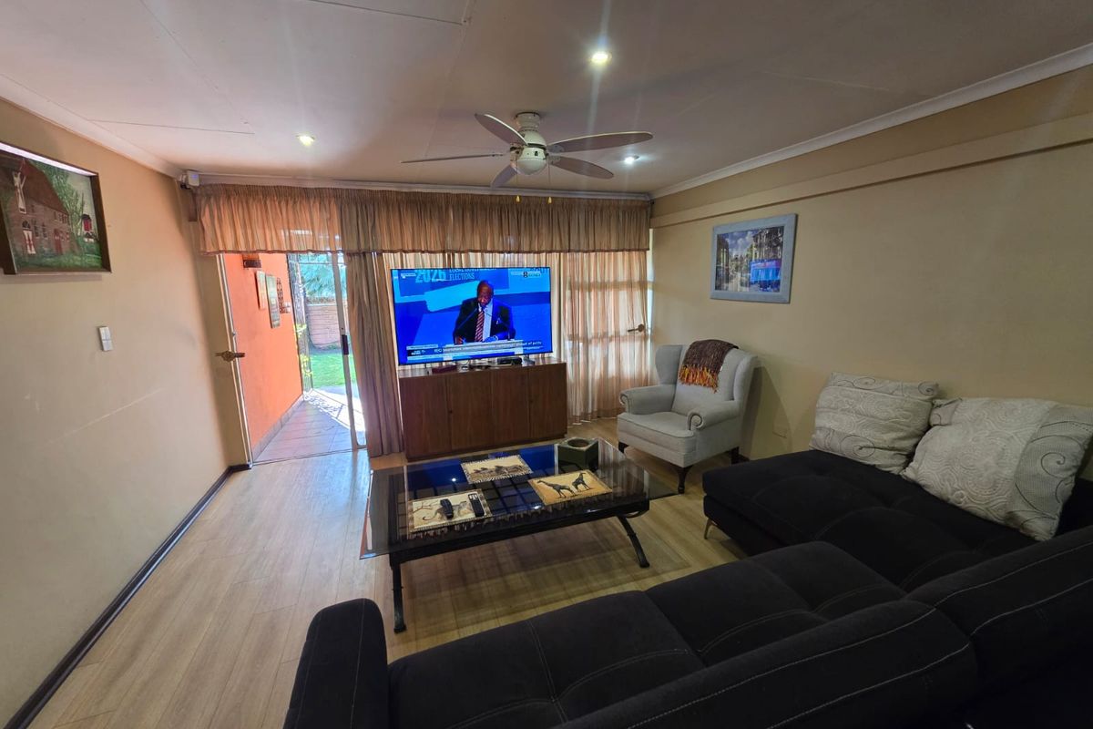 A comfortable living room featuring laminate flooring, a ceiling fan, and direct access to an outdoor patio area through a glass door.
