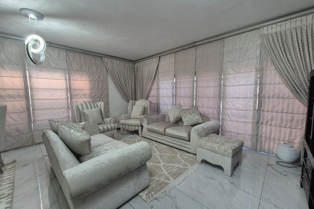 A bright living room featuring polished marble-look floor tiles and extensive floor-to-ceiling window treatments.