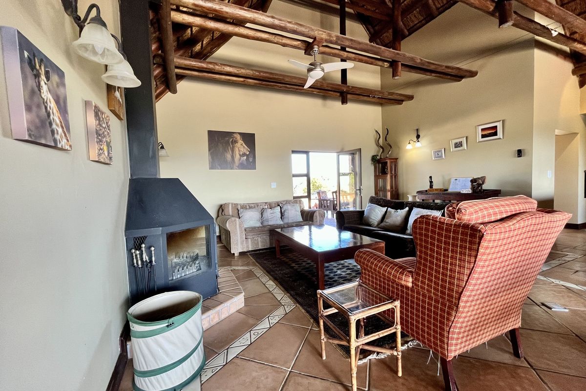 Spacious living room featuring a high vaulted thatched ceiling with exposed timber beams, tiled flooring, and a built-in fireplace.