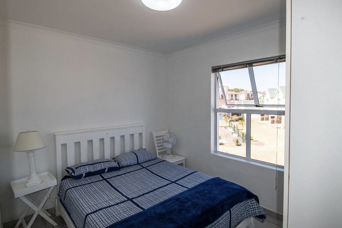 A compact bedroom featuring a window with exterior views, neutral walls, and tiled flooring.