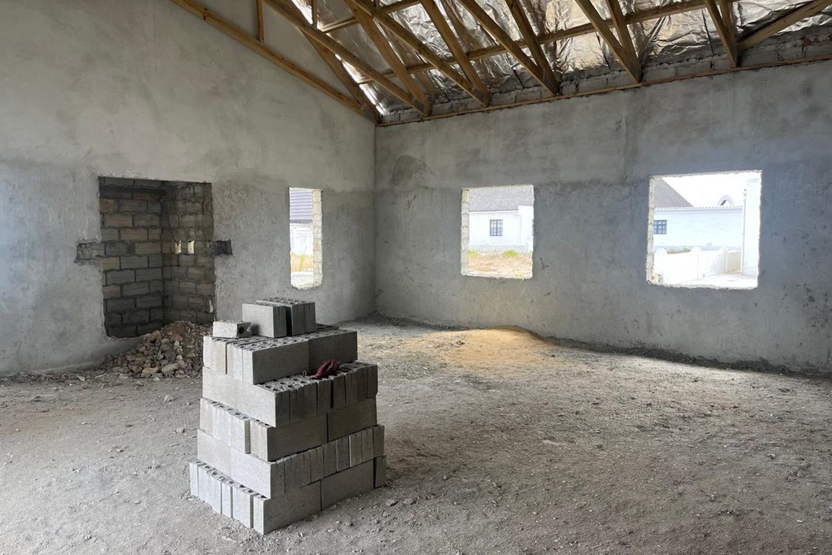 An unfinished interior space featuring exposed timber roof trusses, reflective insulation, and raw cement walls, offering a blank canvas for custom interior design.