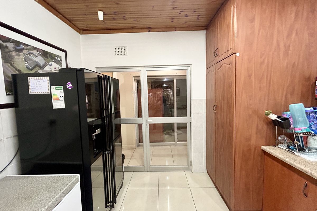 Kitchen area featuring tiled flooring, wooden ceiling paneling, and built-in wooden cabinetry with access to an adjacent room through a glass-paneled door.