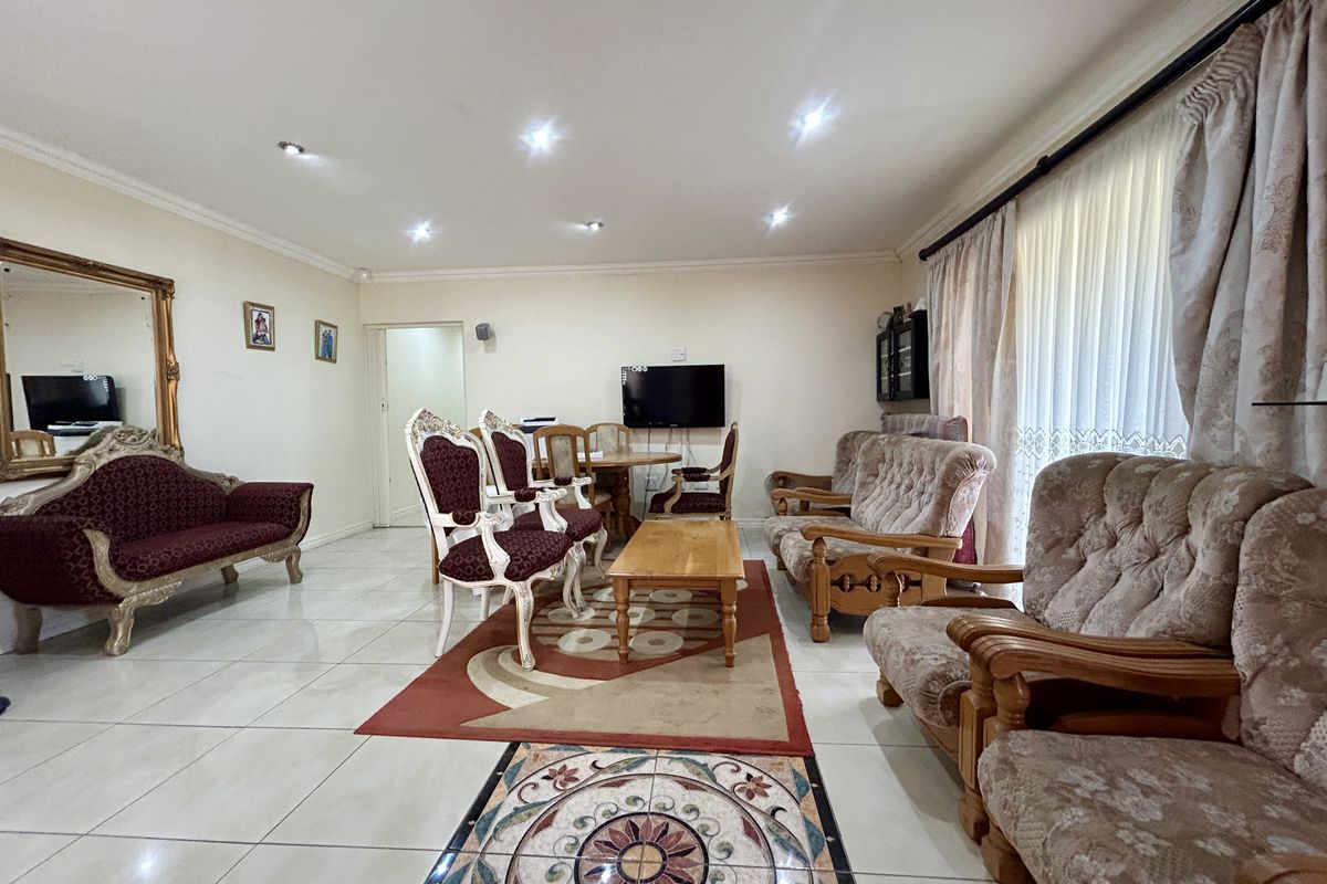 Spacious living room featuring tiled flooring, recessed ceiling lighting, and large windows with curtain tracks, offering a bright and functional living space.