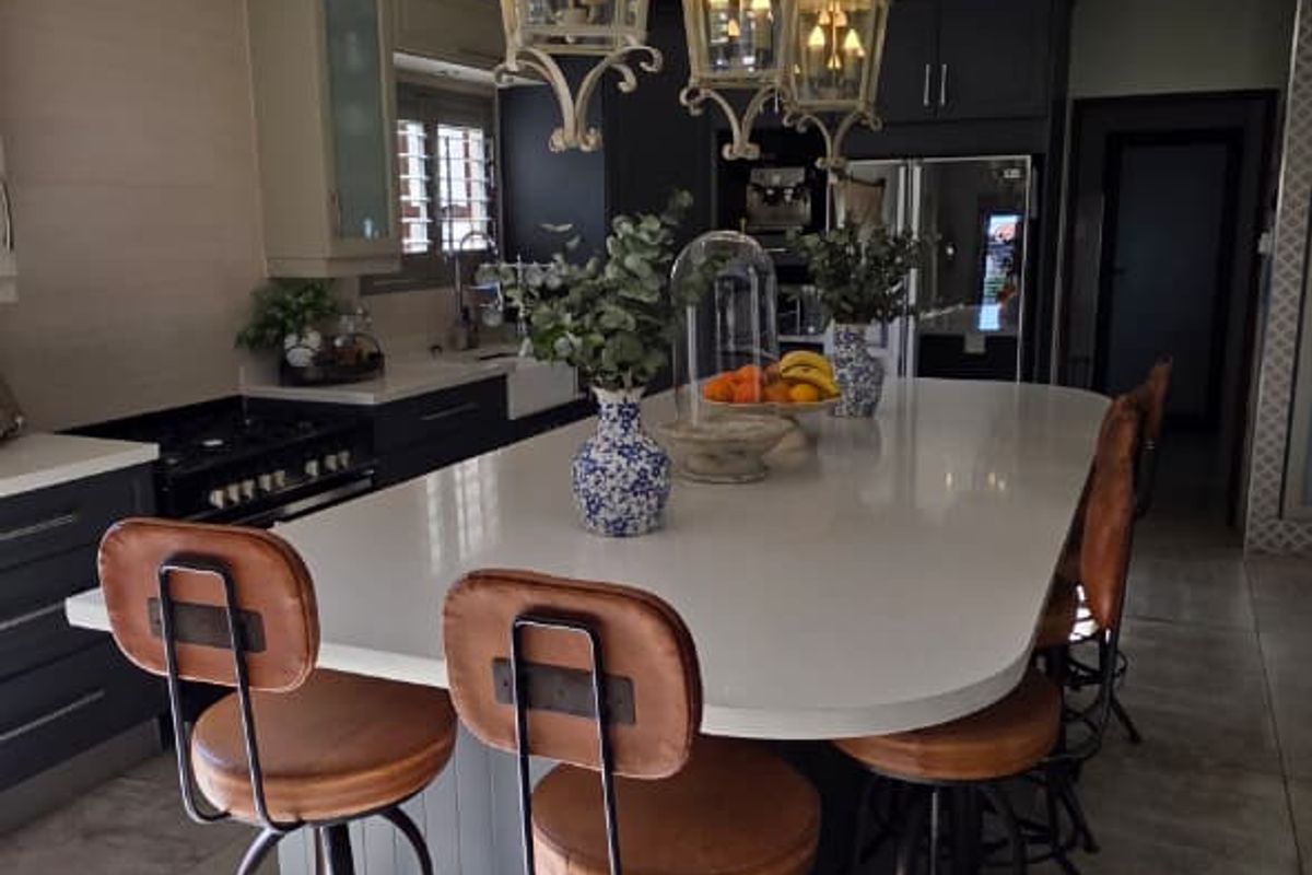 A well-appointed kitchen featuring a large central island with stone countertops, custom cabinetry, and decorative pendant lighting.