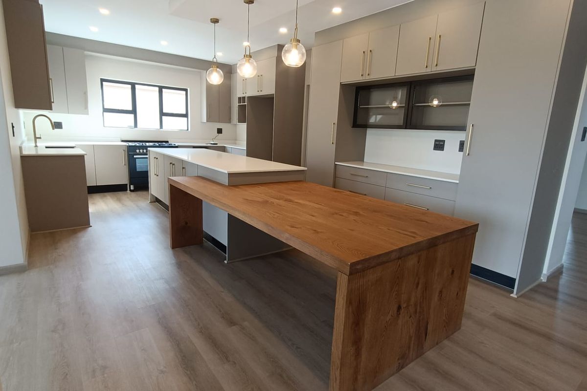 Modern kitchen featuring sleek cabinetry, a central island with a wooden breakfast bar, integrated storage, and high-quality finishes throughout.