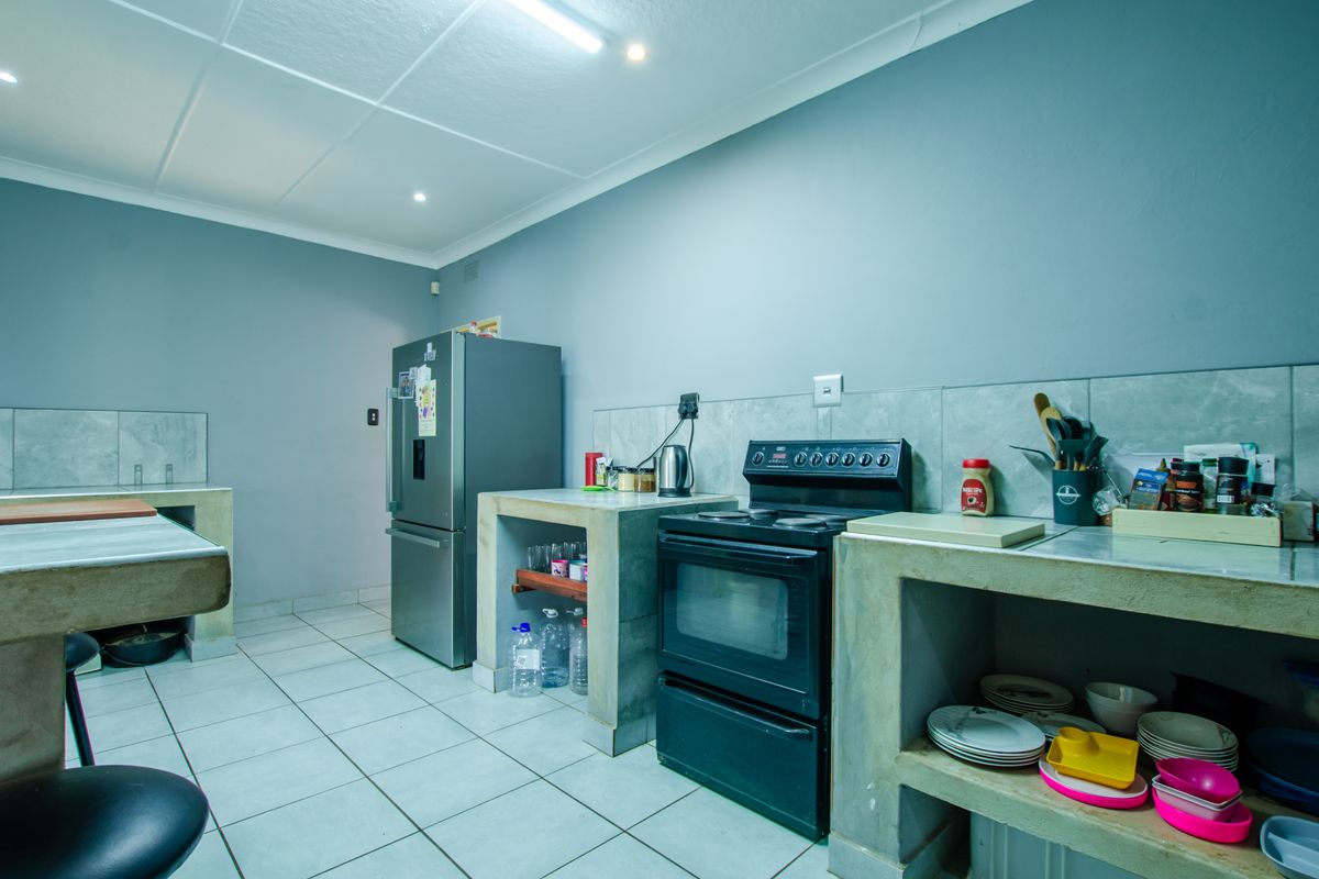 Functional kitchen featuring custom concrete base cabinetry, tiled flooring, and a freestanding electric stove with integrated splashback tiling.