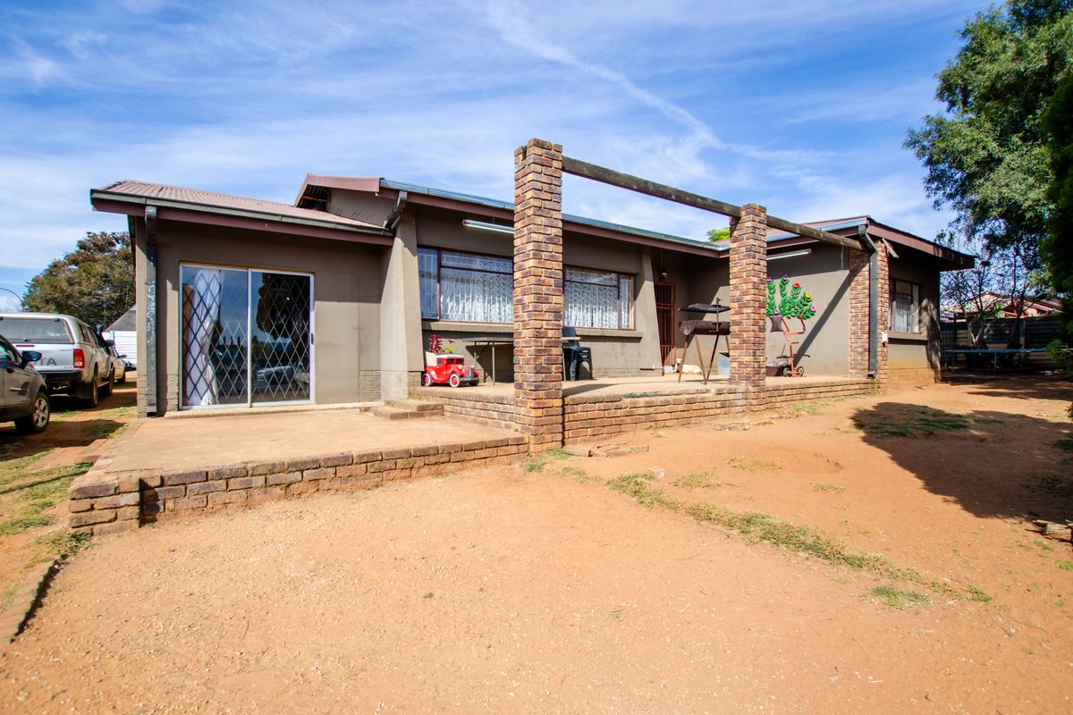 Rear view of the house featuring a brick patio area with structural pillars, sliding glass doors, and access to the garden.