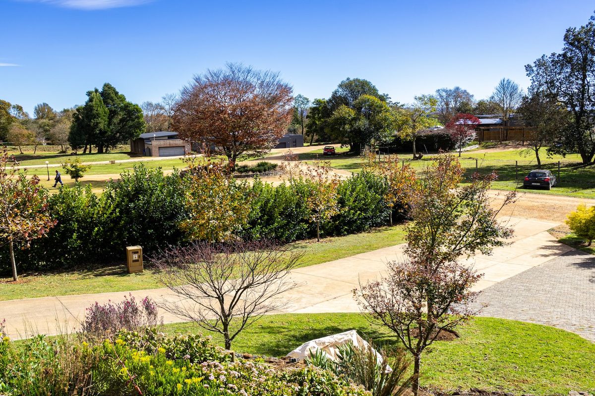 An elevated view of a spacious residential plot featuring manicured lawns, mature trees, paved driveways, and established garden landscaping.