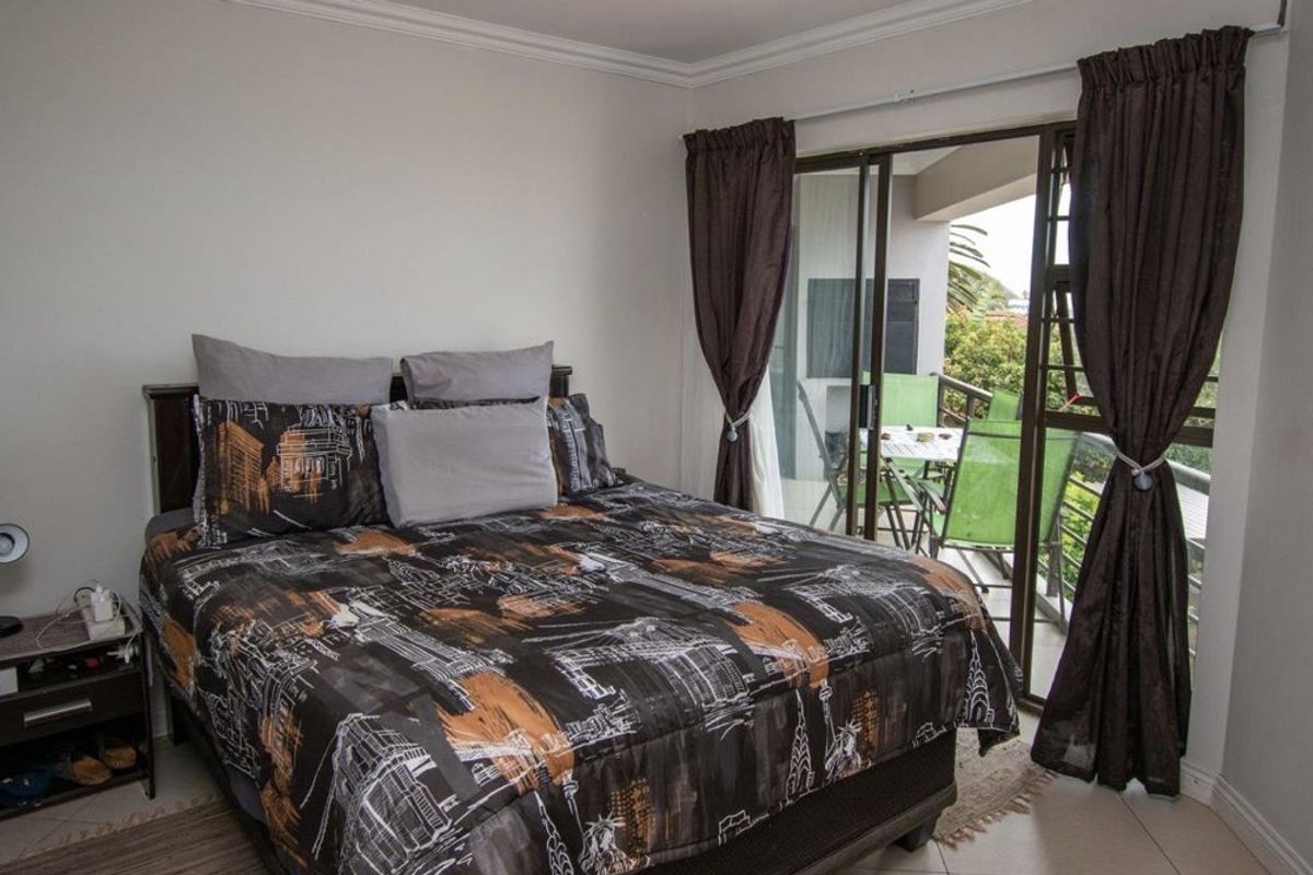 A bedroom featuring tiled flooring and a sliding glass door that provides direct access to an outdoor balcony area.