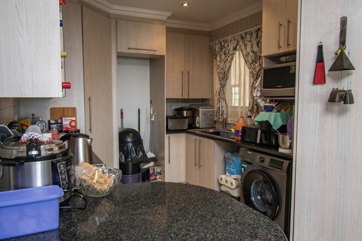Compact kitchen featuring granite countertops, light wood-finish cabinetry, integrated washing machine, and built-in microwave, offering a functional layout for apartment living.