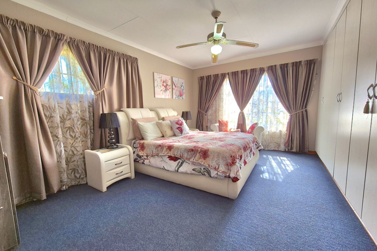 Spacious bedroom featuring built-in cupboards, a ceiling fan, and large windows allowing for ample natural light.
