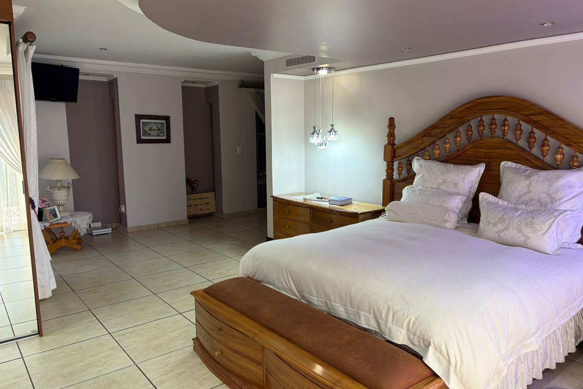 Spacious bedroom featuring tiled flooring, a recessed ceiling design with integrated lighting, and built-in bedside cabinetry.