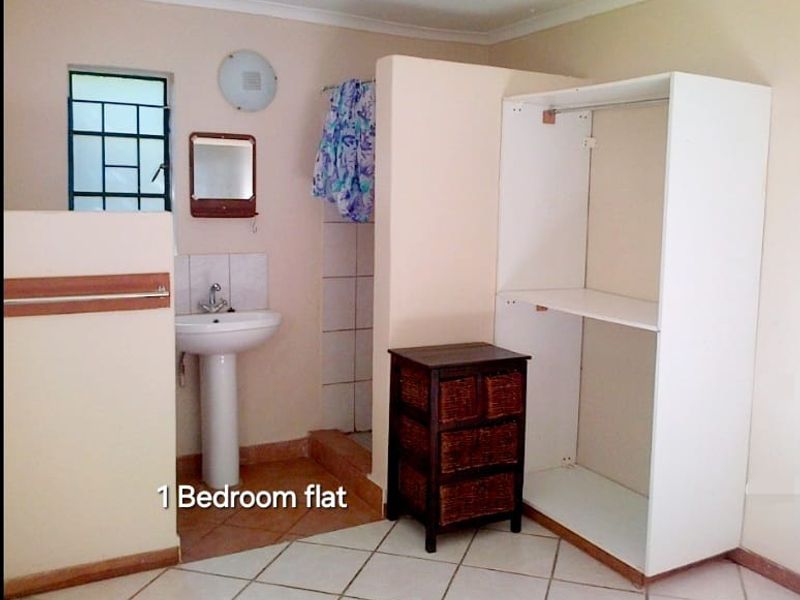 A functional bedroom area featuring an open-plan en-suite bathroom with a pedestal basin and tiled flooring.