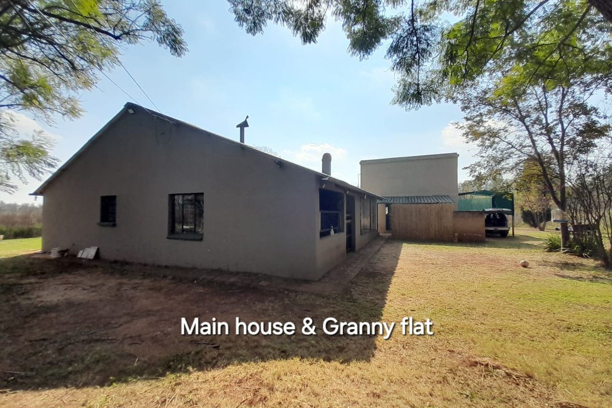 Exterior view of the main farmhouse and attached granny flat, featuring a simple structure set within a spacious rural garden area.