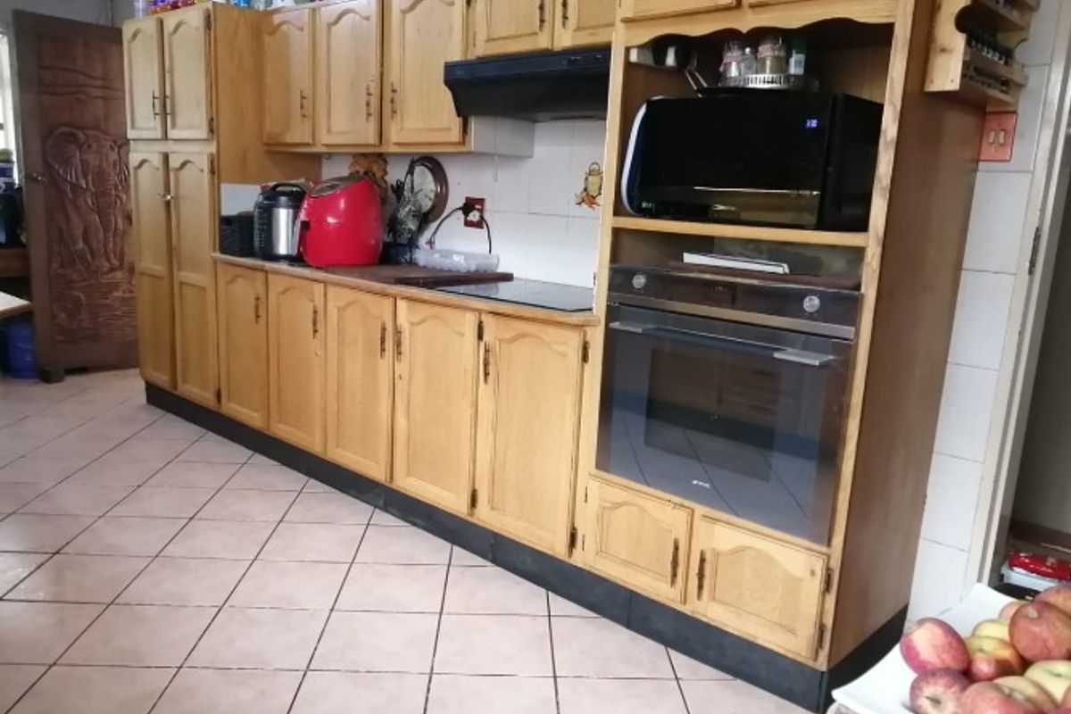 A functional kitchen featuring traditional wooden cabinetry, a built-in oven, an extractor fan, and tiled flooring with a tiled backsplash.
