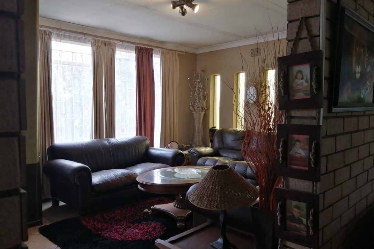 A cozy living room featuring exposed brick architectural elements, tiled flooring, and large windows that provide ample natural light.