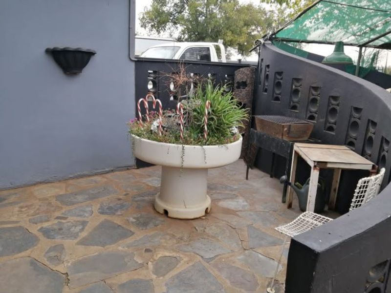 A small outdoor patio area featuring stone paving and a decorative breeze block wall, providing a compact space for outdoor relaxation.