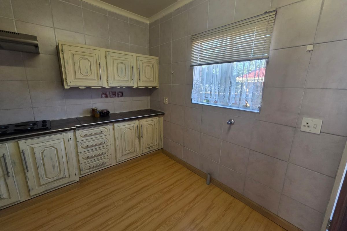 A functional kitchen featuring light-toned cabinetry, a built-in hob with extractor fan, and full-height wall tiling.