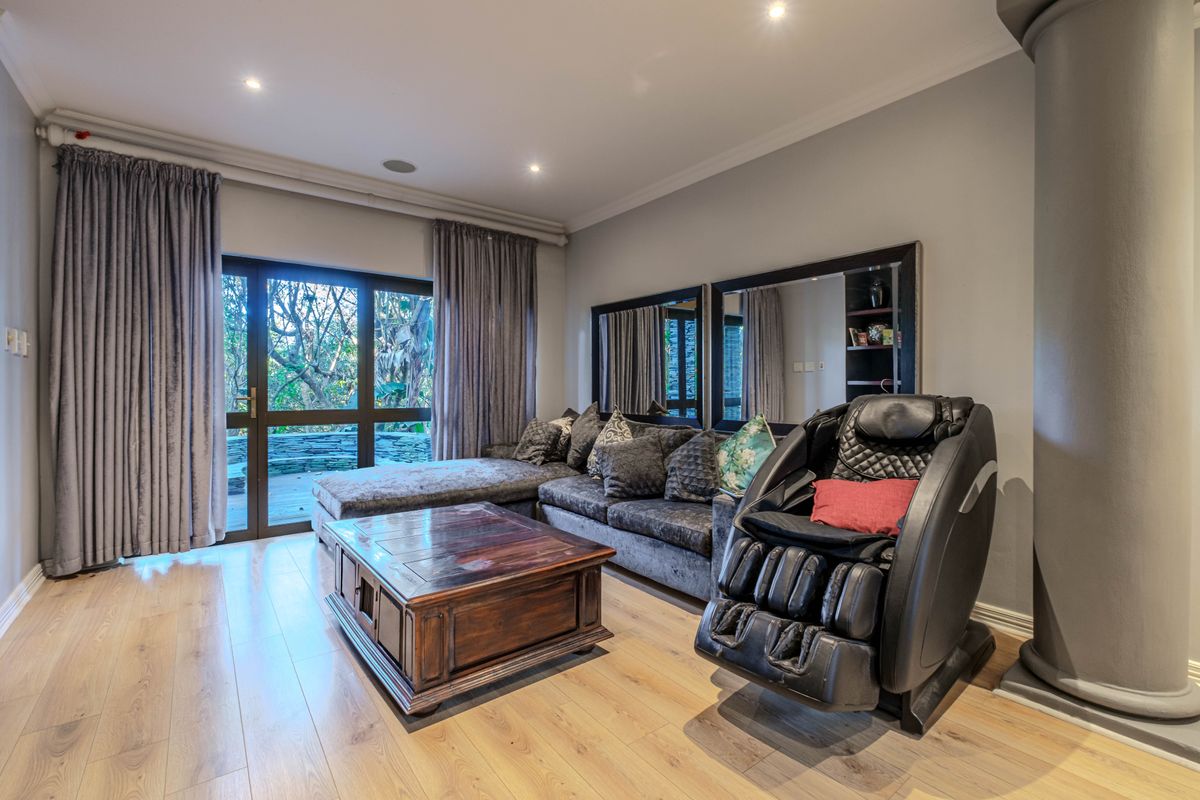 A well-maintained living room featuring light laminate flooring, recessed lighting, and a large sliding glass door providing access to the outdoor area.