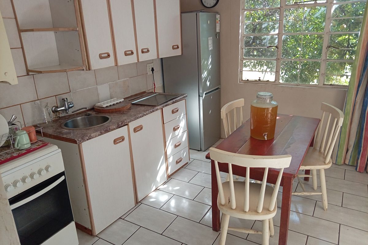 A dated kitchen featuring original cabinetry, tiled flooring, and a small dining area, offering potential for modernization and renovation.