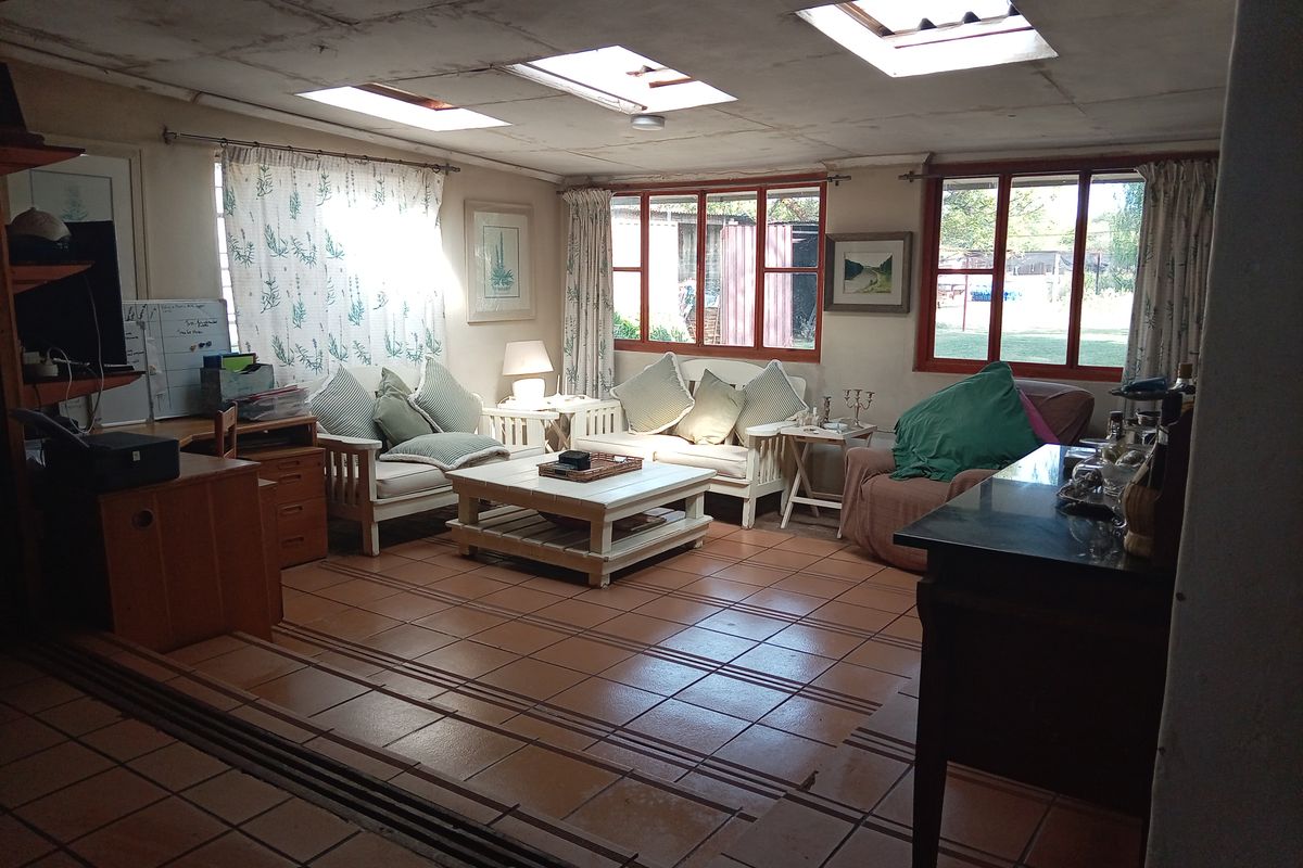 Spacious living room featuring tiled flooring, multiple skylights, and large windows providing natural light and garden views.