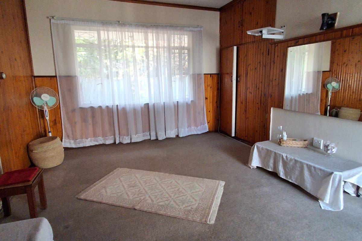 A living room featuring dated wood wall paneling, carpet flooring, and built-in storage cupboards, offering a blank canvas for potential modernization.