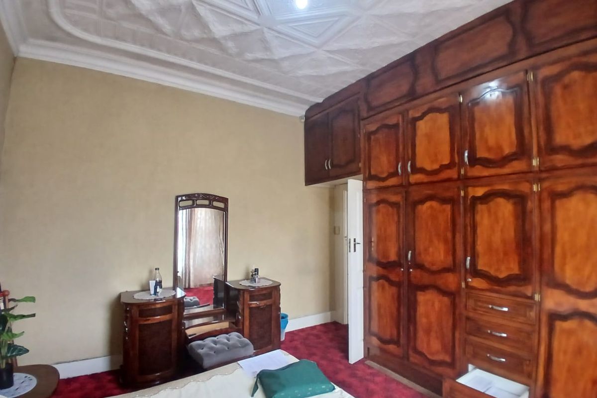 A bedroom featuring extensive built-in wooden cabinetry with overhead storage and a decorative patterned ceiling.