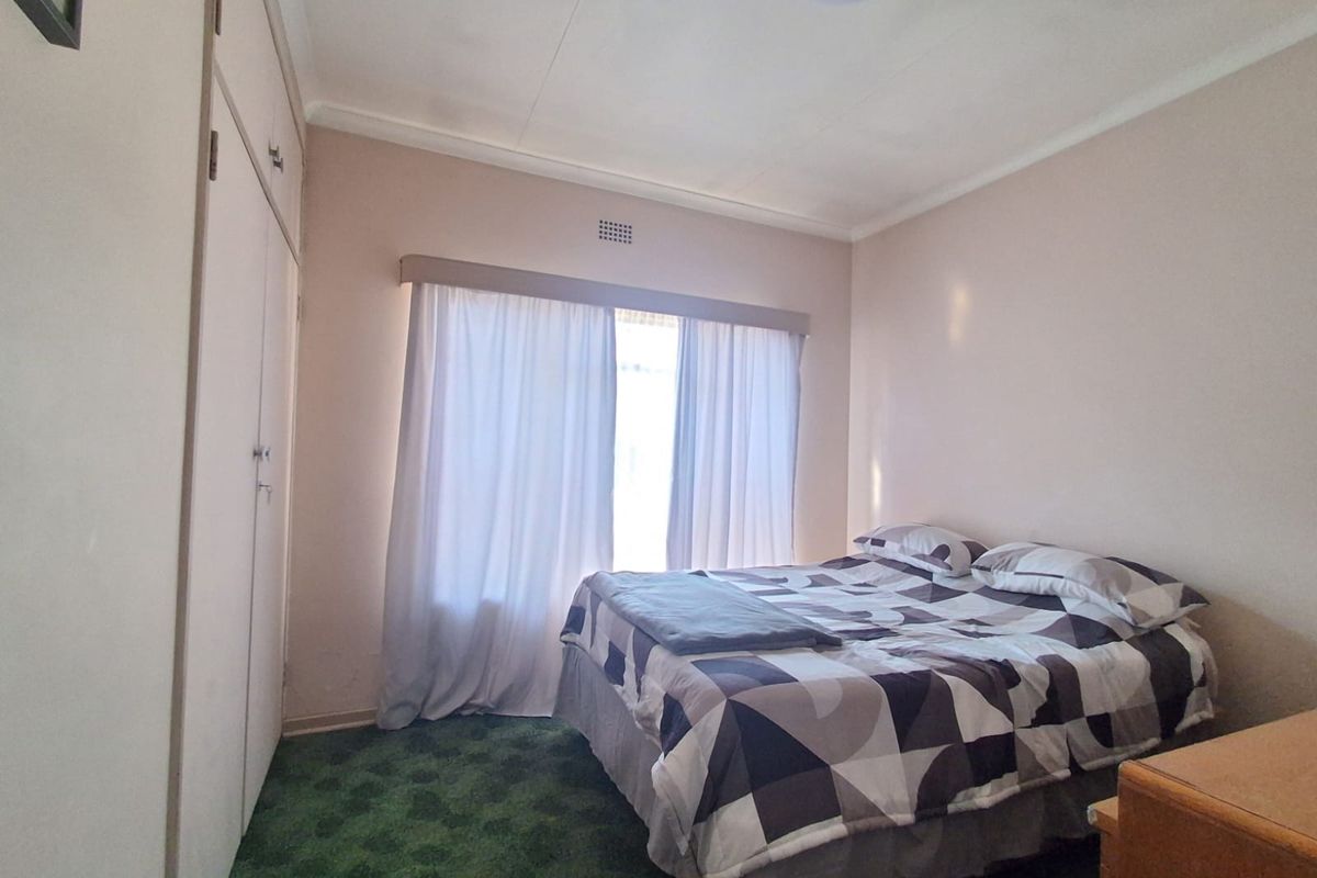 A bedroom featuring built-in cupboards and carpeted flooring, offering a functional space with potential for modernization.